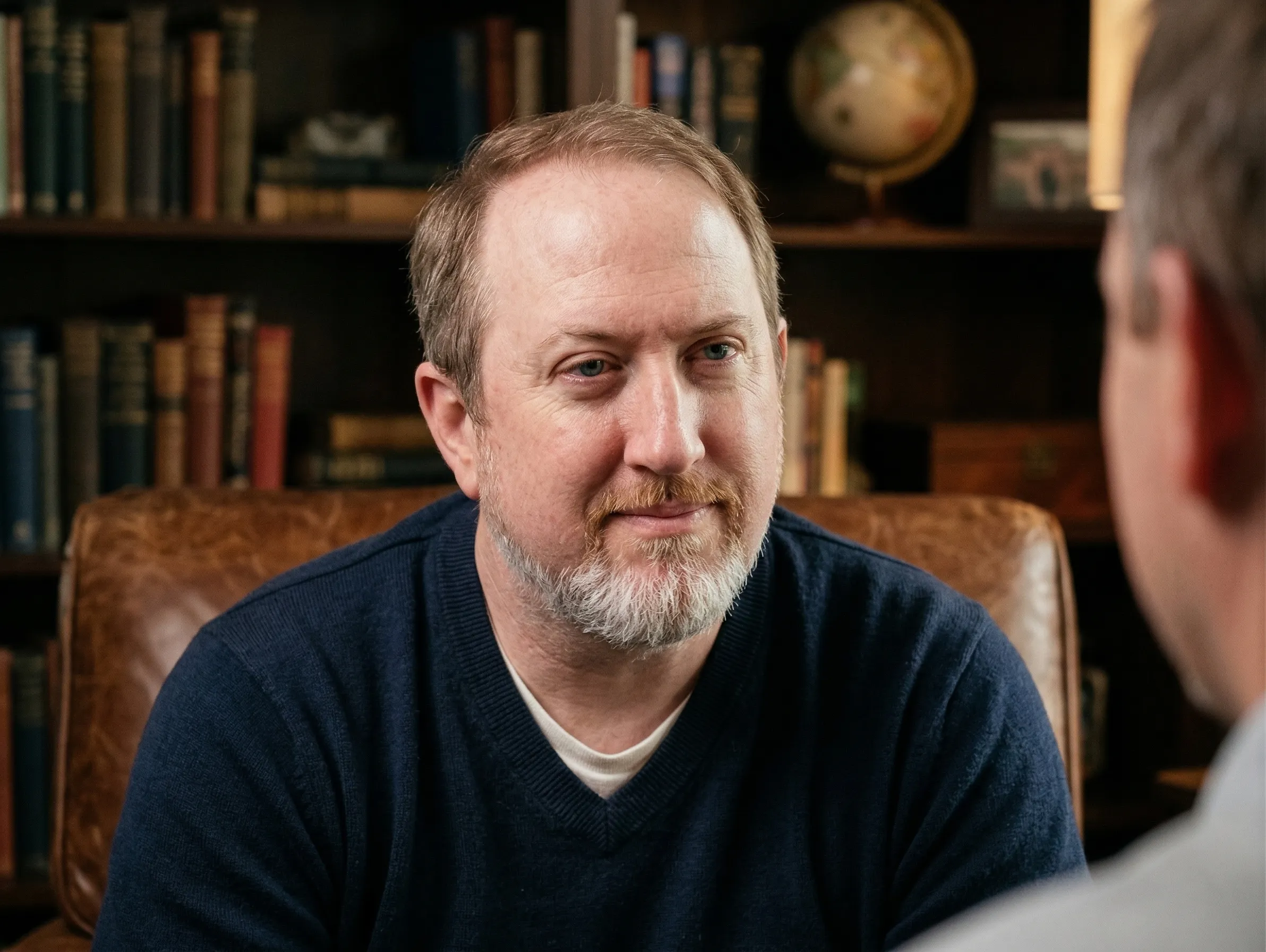 Philip Jarrell in a warm library, leaning in and listening attentively to the person across from him